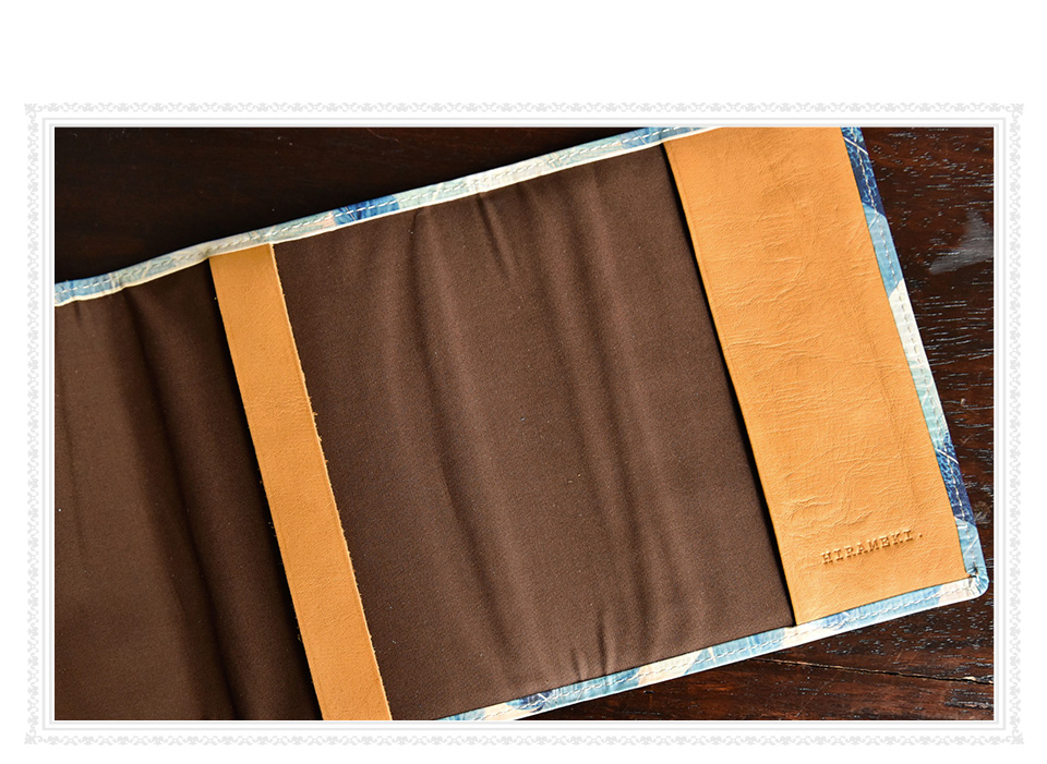 ブックカバーの内側、ブラウンの綿生地と、右側の革の下部に入ったHIRAMEKI.のブランドロゴの刻印イメージ